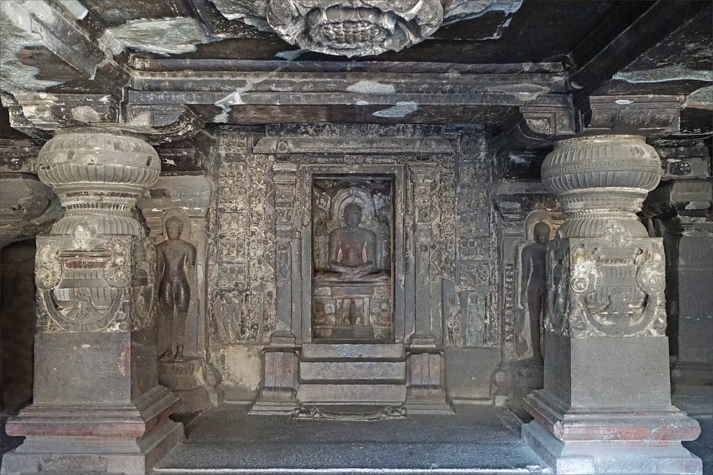 Panoramic exterior of Ellora Caves with rock-cut cave entrances along a basalt cliff